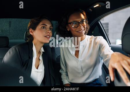 Deux collègues assis sur une banquette arrière d'un taxi et à l'écart Banque D'Images