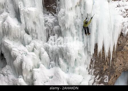 Un grimpeur sur glace masculin solo utilise l'équipement d'escalade de travailler son chemin jusqu'à Upper Falls congelé Johnston Canyon Banque D'Images