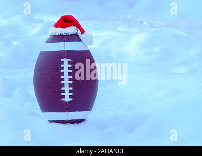 Le football américain wearing a Santa Claus Hat sur la neige Banque D'Images