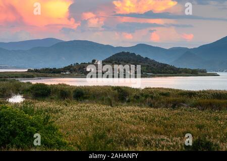 Vue sur les roseaux au lac Mikri Prespa vers l'île d'Agios Achillios au coucher du soleil, Macédoine, Grèce du Nord. Banque D'Images