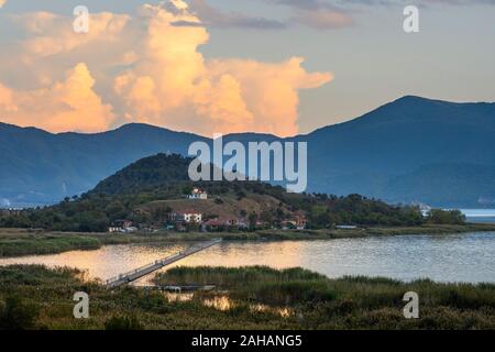 Vue sur les roseaux au lac Mikri Prespa vers l'île d'Agios Achillios au coucher du soleil, Macédoine, Grèce du Nord. Banque D'Images