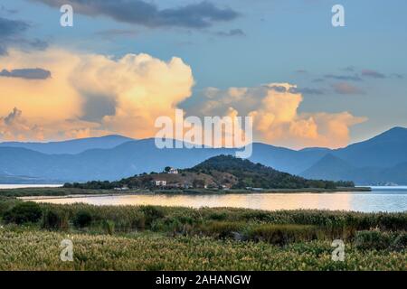 Vue sur les roseaux au lac Mikri Prespa vers l'île d'Agios Achillios au coucher du soleil, Macédoine, Grèce du Nord. Banque D'Images