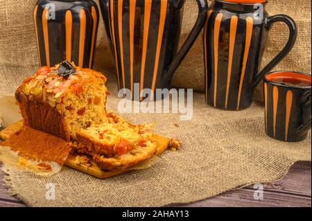 Tranches d'un gâteau de Noël fait maison sur une planche en bois et céramiques de table sur une table recouverte d'un tissu de fabrication locale Banque D'Images