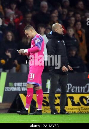 Gardien de Manchester City Ederson (à gauche) après avoir été hors promenades un carton rouge montre que le Pep Guardiola cherche sur au cours de la Premier League match à Molineux, Wolverhampton. Banque D'Images