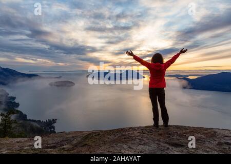 Fille d'aventure au sommet d'une montagne au coucher du soleil Banque D'Images