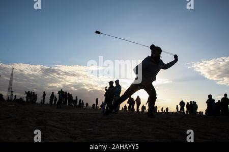 Rafah, Gaza. Dec 27, 2019. Un Palestinien utilise une fronde pour lancer des pierres au cours d'affrontements suite à une manifestation le long de la frontière avec Israël à l'est de Rafah dans le sud de la bande de Gaza. le vendredi, Décembre 27, 2019. 29 Palestiniens à Gaza, manifestations retour le long de la frontière fortifiée avec Israël, des factions dans la bande de Gaza, a déclaré jeudi. Photo par Ismael Mohamad/UPI UPI/Alamy Crédit : Live News Banque D'Images