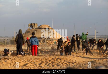 Rafah, Gaza. Dec 27, 2019. Des manifestants palestiniens affronter des soldats israéliens lors d'affrontements avec les forces israéliennes de l'autre côté de la clôture de barbelés suite à une manifestation le long de la frontière avec Israël à l'est de Rafah dans le sud de la bande de Gaza Vendredi, 27 Dacember, 2019. Les Palestiniens de Gaza, manifestations retour le long de la frontière fortifiée avec Israël, des factions dans la bande de Gaza, a déclaré jeudi, Photo par Ismael Mohamad/UPI UPI/Alamy Crédit : Live News Banque D'Images