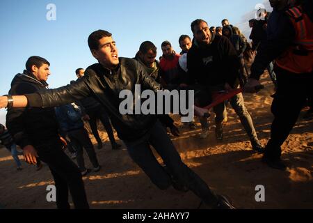 Rafah, Gaza. Dec 27, 2019. Les ambulanciers palestiniens emporter un manifestant blessé lors de heurts après une manifestation le long de la frontière avec Israël à l'est de Rafah dans le sud de la bande de Gaza, le vendredi 27 Décembre, 2019. Les Palestiniens de Gaza, manifestations retour le long de la frontière fortifiée avec Israël, des factions dans la bande de Gaza, a déclaré jeudi. Photo par Ismael Mohamad/UPI UPI/Alamy Crédit : Live News Banque D'Images
