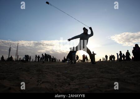 Rafah, Gaza. Dec 27, 2019. Un Palestinien utilise une fronde pour lancer des pierres au cours d'affrontements suite à une manifestation le long de la frontière avec Israël, à l'est de Rafah dans le sud de la bande de Gaza, le vendredi 27 Décembre, 2019. Les Palestiniens de Gaza, manifestations retour le long de la frontière fortifiée avec Israël, des factions dans la bande de Gaza, a déclaré jeudi. Photo par Ismael Mohamad/UPI/UP Crédit : Alamy Live News Banque D'Images