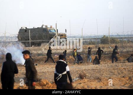 Rafah, Gaza. Dec 27, 2019. Des manifestants palestiniens affronter des soldats israéliens lors d'affrontements avec les forces israéliennes de l'autre côté de la clôture de barbelés suite à une manifestation le long de la frontière avec Israël à l'est de Rafah dans le sud de la bande de Gaza Vendredi, 27 Dacember, 2019. Les Palestiniens de Gaza, manifestations retour le long de la frontière fortifiée avec Israël, des factions dans la bande de Gaza, a déclaré jeudi, Photo par Ismael Mohamad/UPI UPI/Alamy Crédit : Live News Banque D'Images