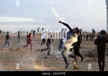 Rafah, Gaza. Dec 27, 2019. Un manifestant palestinien retour jette une bombe lacrymogène tiré par les forces israéliennes au cours d'affrontements suite à une manifestation le long de la frontière avec Israël à l'est de Rafah dans le sud de la bande de Gaza, le vendredi 27 Décembre, 2019. Les Palestiniens de Gaza, manifestations retour le long de la frontière fortifiée avec Israël, des factions dans la bande de Gaza, a déclaré jeudi. Photo par Ismael Mohamad/UPI UPI/Alamy Crédit : Live News Banque D'Images