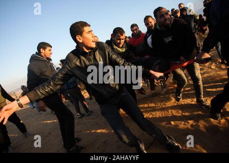 Rafah, Gaza. Dec 27, 2019. Les ambulanciers palestiniens emporter un manifestant blessé lors de heurts après une manifestation le long de la frontière avec Israël à l'est de Rafah dans le sud de la bande de Gaza, le vendredi 27 Décembre, 2019. Les Palestiniens de Gaza, manifestations retour le long de la frontière fortifiée avec Israël, des factions dans la bande de Gaza, a déclaré jeudi. Photo par Ismael Mohamad/UPI UPI/Alamy Crédit : Live News Banque D'Images