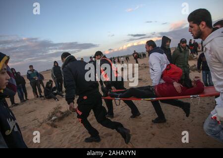 Rafah, Gaza. Dec 27, 2019. Les ambulanciers palestiniens emporter un manifestant blessé lors de heurts après une manifestation le long de la frontière avec Israël à l'est de Rafah dans le sud de la bande de Gaza. le vendredi 27 décembre 2019. Les Palestiniens de Gaza, manifestations retour le long de la frontière fortifiée avec Israël, des factions dans la bande de Gaza, a déclaré jeudi, Photo par Ismael Mohamad/UPI UPI/Alamy Crédit : Live News Banque D'Images