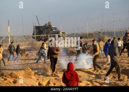 Rafah, Gaza. Dec 27, 2019. Des manifestants palestiniens affronter des soldats israéliens lors d'affrontements avec les forces israéliennes de l'autre côté de la clôture de barbelés suite à une manifestation le long de la frontière avec Israël à l'est de Rafah dans le sud de la bande de Gaza Vendredi, 27 Dacember, 2019. Les Palestiniens de Gaza, manifestations retour le long de la frontière fortifiée avec Israël, des factions dans la bande de Gaza, a déclaré jeudi, Photo par Ismael Mohamad/UPI UPI/Alamy Crédit : Live News Banque D'Images