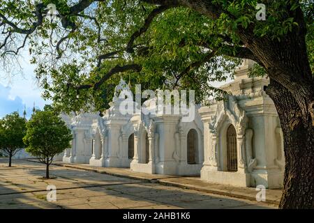 Les arbres ombragés et lumière pommelé au crépuscule à la Pagode Kuthodaw, un stupa bouddhiste au pied de Mandalay Hill qui détient la plus grande réserve, à Mandalay, au Myanmar, anciennement connu sous le nom de Birmanie Banque D'Images