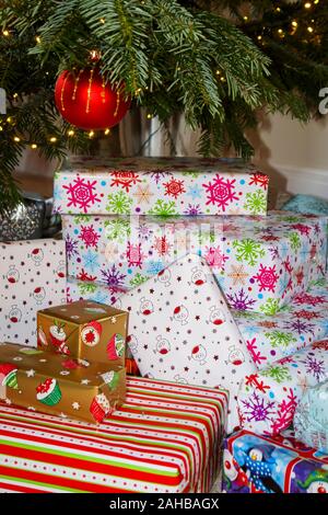 Pile de traditionnelle colorée typique de Noël ou des cadeaux emballés présente sous un arbre de Noël au Royaume-Uni des fêtes Banque D'Images