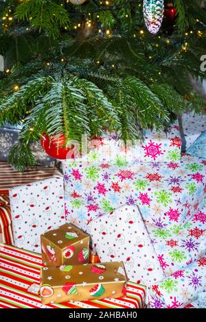 Pile de traditionnelle colorée typique de Noël ou des cadeaux emballés présente sous un arbre de Noël au Royaume-Uni des fêtes Banque D'Images