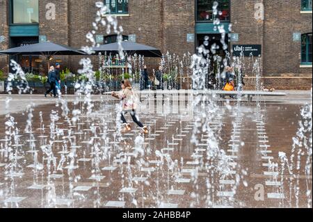 Jeune fille passe par une fontaine d'eau à Londres, au Royaume-Uni. Banque D'Images