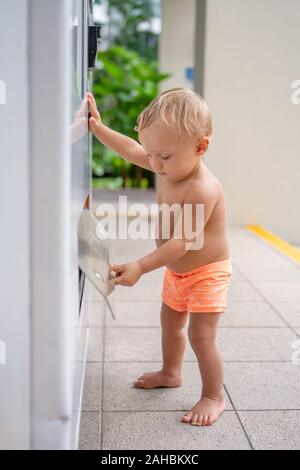 Un petit garçon à la découverte d'un distributeur automatique Banque D'Images