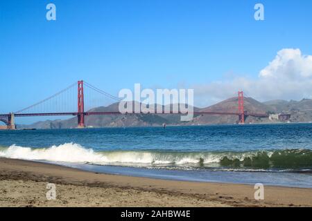 Orange international Golden Gate Bridge avec des vagues se brisant sur le terrain zone de loisirs à Crissy plage en face. San Francisco, États-Unis. Banque D'Images