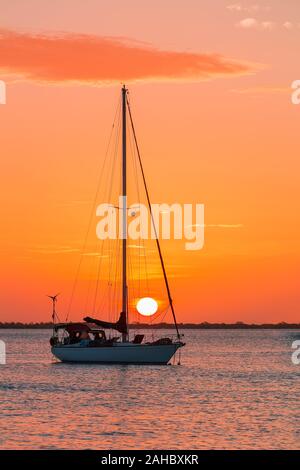 Un seul bateau à voile sur la mer à l'établissement soleil orange Banque D'Images