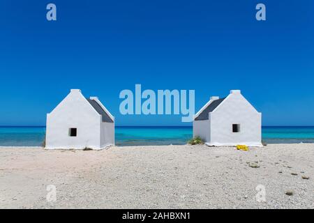 Deux maisons d'esclaves blancs sur la plage avec la mer bleue sur l'île de Bonaire Banque D'Images