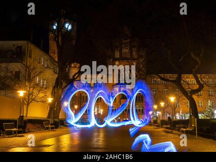 Berlin, Allemagne. Dec 21, 2019. Un homme écrit l'année 2020 en face de l'hôtel de ville de Köpenick avec lumière colorée. (Longue exposition) Crédit : Paul Zinken/dpa/Alamy Live News Banque D'Images