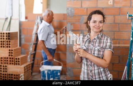 Une femme habile engagés dans des travaux de rénovation à l'intérieur, travaillant avec une truelle de plâtrage Banque D'Images