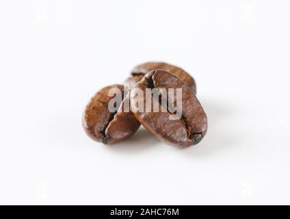 Trois grains de café torréfiés sur fond blanc Banque D'Images