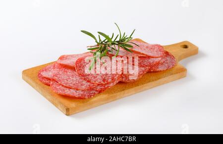Minces tranches de salami sausage sur planche à découper en bois Banque D'Images