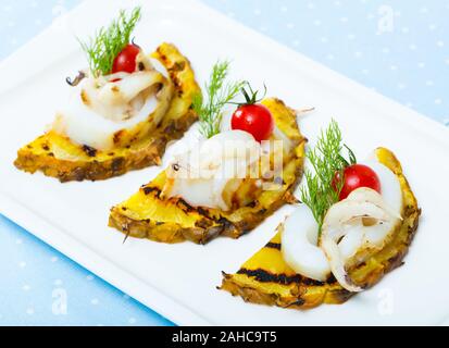 Droit de sepia frits sur une grille avec de l'ananas, de tomates cerises et de la sauce chili sur la plaque à l'intérieur. Banque D'Images