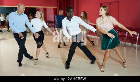 Les jeunes gens sourire active la pratique de mouvements de danse lindy hop en classe Banque D'Images