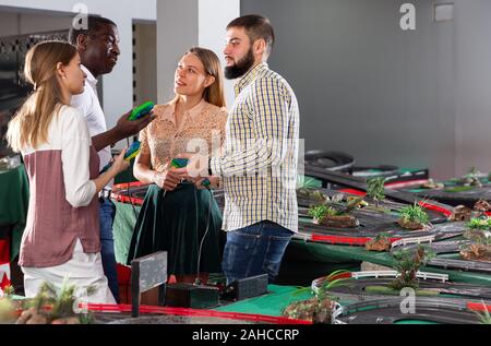 Les amis de discuter les résultats de jeu sur piste de voiture de slot racing jouet Banque D'Images
