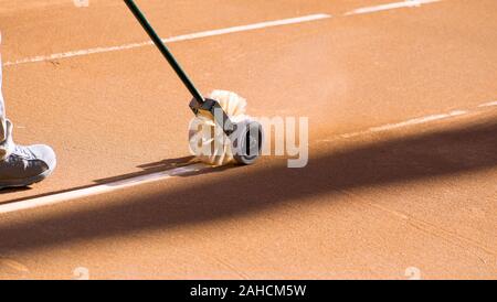 Le nettoyage des lignes sur un court de tennis en terre battue. Banque D'Images