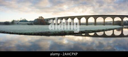 Les arches de Arthington viaduc en basse Wharfedale, Yorkshire, se reflètent dans les eaux calmes de la rivière Wharfe frosty sur un matin d'automne. Banque D'Images