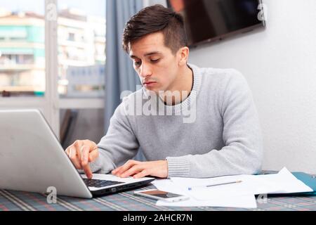 Jeune homme bouleversé compte budget familial on laptop Banque D'Images