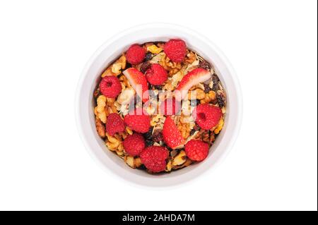 Vue de dessus d'un granola bio faits maison avec l'avoine, les noix, les framboises et les fraises dans un bol blanc Banque D'Images