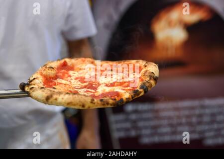 Le cuisinier tire un délicieux des pizzas italiennes traditionnelles de la combustion four. Banque D'Images