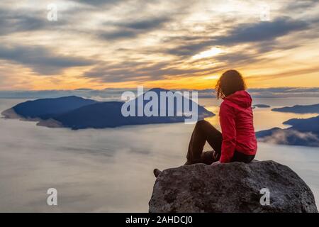 Fille d'aventure au sommet d'une montagne au coucher du soleil Banque D'Images