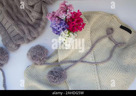 Close-up of blouse en tricot et chapeau avec pom pom, concept d'hiver, jacinthe colorés de fleurs dans un vase Banque D'Images