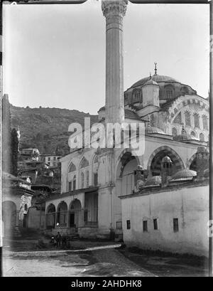 La mosquée Muradiye Külliyesi, Manisa, Street view avec un groupe d'autochtones assis sur la route près de l'entrée. Mosquée Muradiye a été construit par Mimar Sinan à la fin 16. siècle. Manisa est situé dans la partie occidentale de la Turquie. Photographie prise dans les années 1910 sur la plaque de verre, une partie de l'Herry W. Schaefer collection Ottoman. Banque D'Images