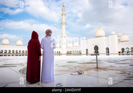 Couple arabe visiter la Grande Mosquée d'Abu Dhabi portant un costume traditionnel vue arrière Banque D'Images