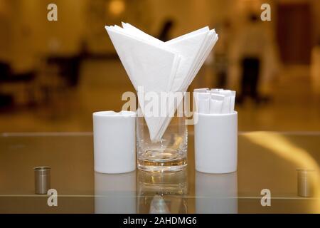 Serviettes blanches dans un métal porte-serviettes, les épices le sel et le poivre sur un woodeglass table, vue panoramique. cure-dent . Une table dans un café ou un restaurant. Banque D'Images