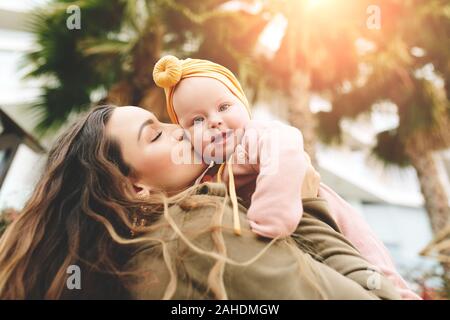 Incroyablement belle mère tenant dans ses bras sa fille et s'embrasser à l'extérieur. Look élégant à la mode. Banque D'Images