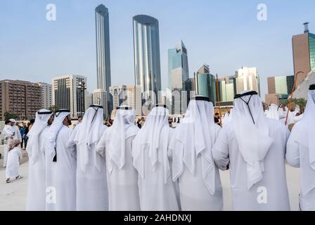 L'arabe hommes debout en tissu traditionnel autour de bâtiments modernes - Culture du Proche-Orient - exécution d'hommes Emirati Al Ayala danse traditionnelle Banque D'Images