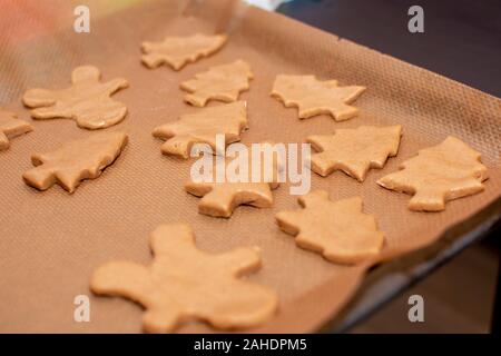 Pas prêt gingerbread cookies sous la forme d'arbres de Noël et de petits hommes se coucher sur papier cuisson close-up. Couleurs chaudes, Selective focus Banque D'Images
