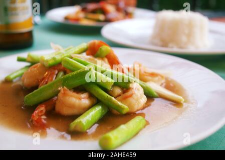 Crevettes sautées et haricots verts marinés dans une sauce aigre-douce, servi avec du riz vapeur dans un restaurant à Phuket, Thaïlande. Banque D'Images