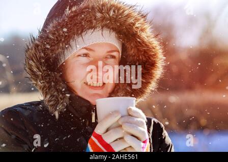 Femme marche dans la rue du port d'écharpe et hat smiling et boire du thé chaud Banque D'Images