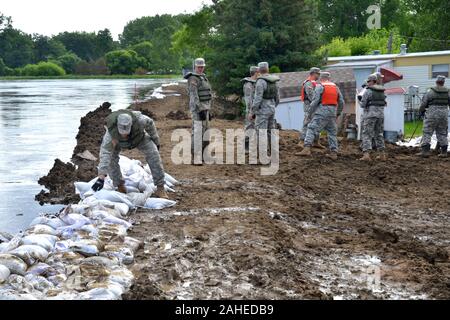 MINOT, N.D. - Les soldats de la Garde nationale du Dakota du Nord, lieux de sacs sur une digue temporaire de Minot, N.D., 22 juin. La ville de Minot appliquée une évacuation obligatoire peu avant 1 h, le U.S. Army Corps of Engineers, district de Saint Paul, avec la Garde nationale du Dakota du Nord, a continué de renforcer les digues temporaires pour permettre aux citoyens touchés par l'évacuation obligatoire de suffisamment de temps pour quitter la zone en toute sécurité. Le Corps continuera à soutenir les autorités locales dans le bassin de la souris pendant la crue historique. Banque D'Images