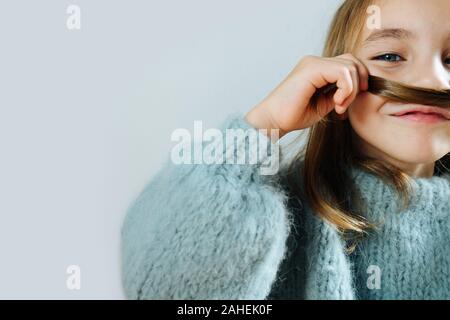 Gros plan d'une petite fille dans un pull bleu pour rire ; faire fake moustache Banque D'Images